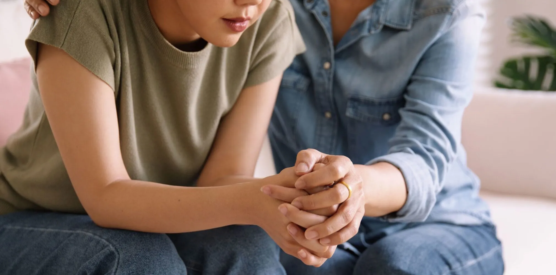 Comforting scene where one person supports another by placing a hand on their shoulder as they sit together, emphasizing empathy and care.